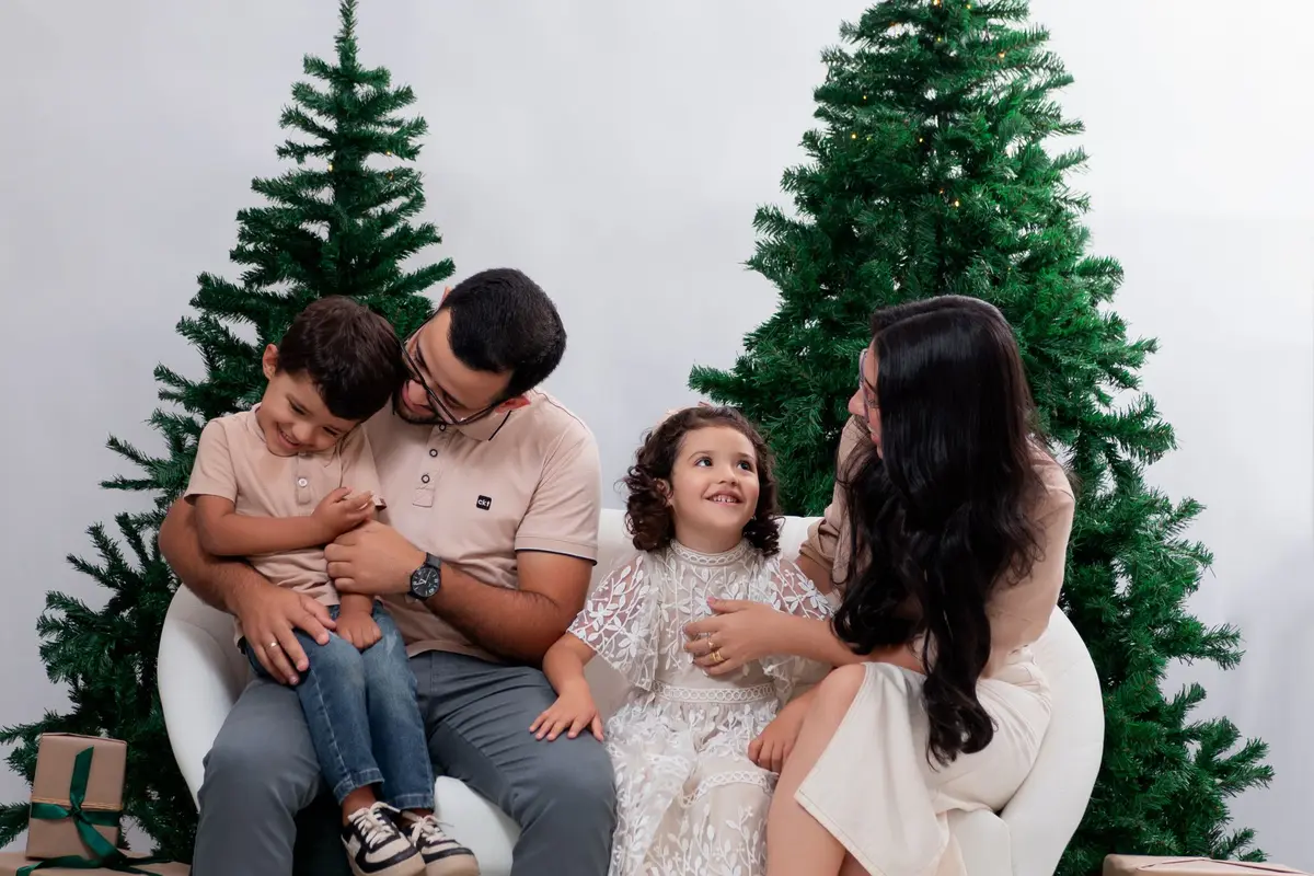Familie sitzt vor zwei beleuchteten Weihnachtsbäumen im Studio