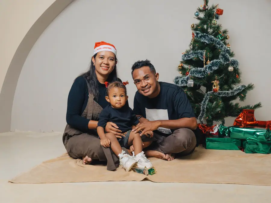 Familie auf einer Decke vor schlichtem Studiohintergrund mit Weihnachtsbaum